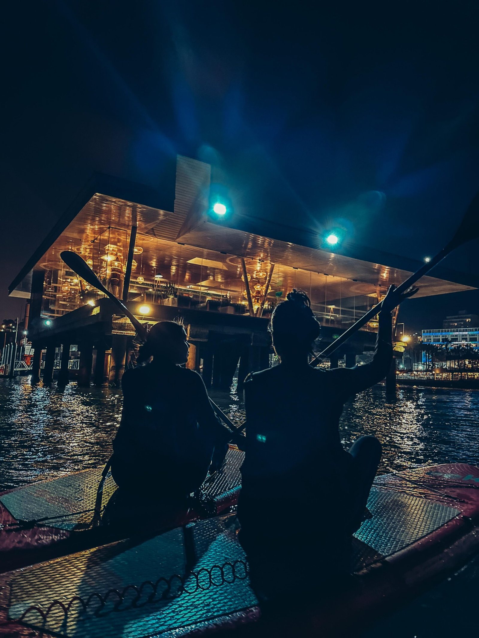 a couple of people sitting on a boat with paddles in the water