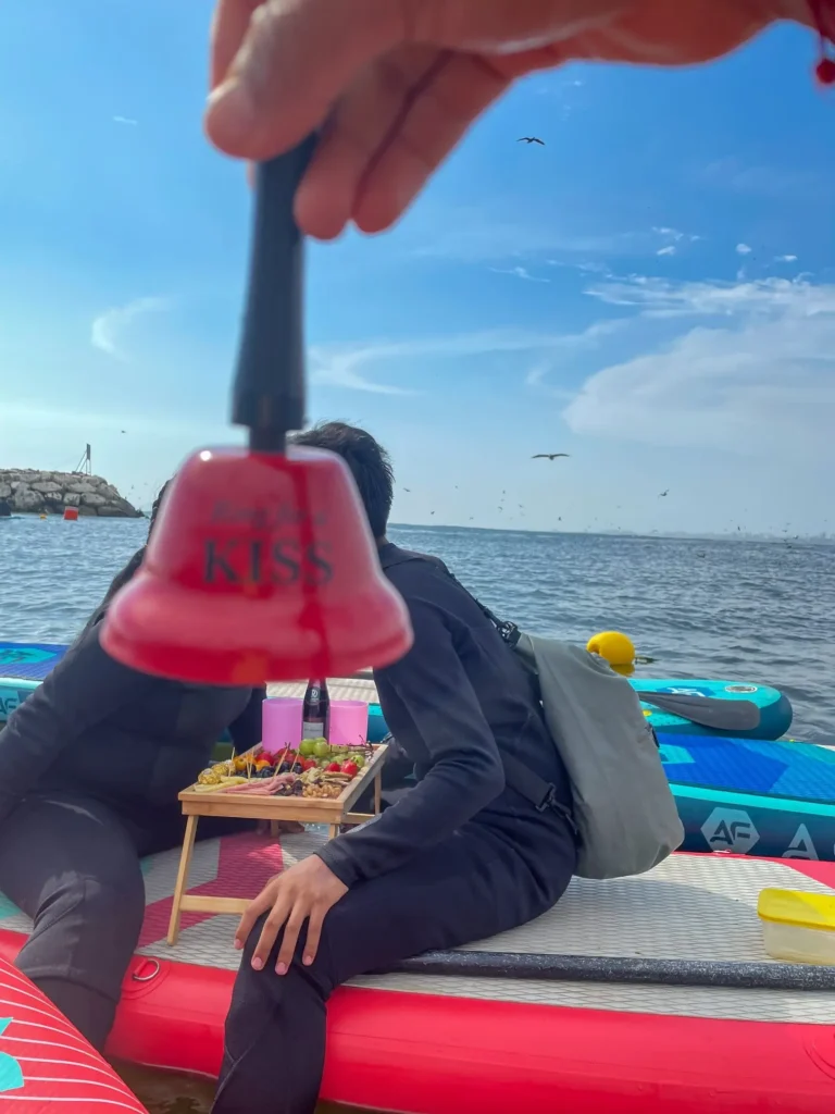 Personas disfrutando picnic y paddleboard en el mar